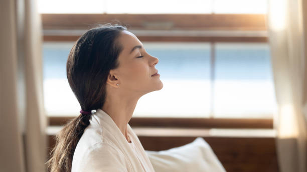 A woman breathing deeply through her nose with her eyes closed.