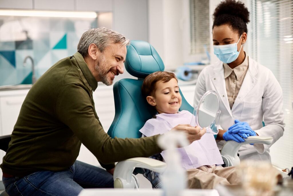 A father and son happily smiling at the dentist.