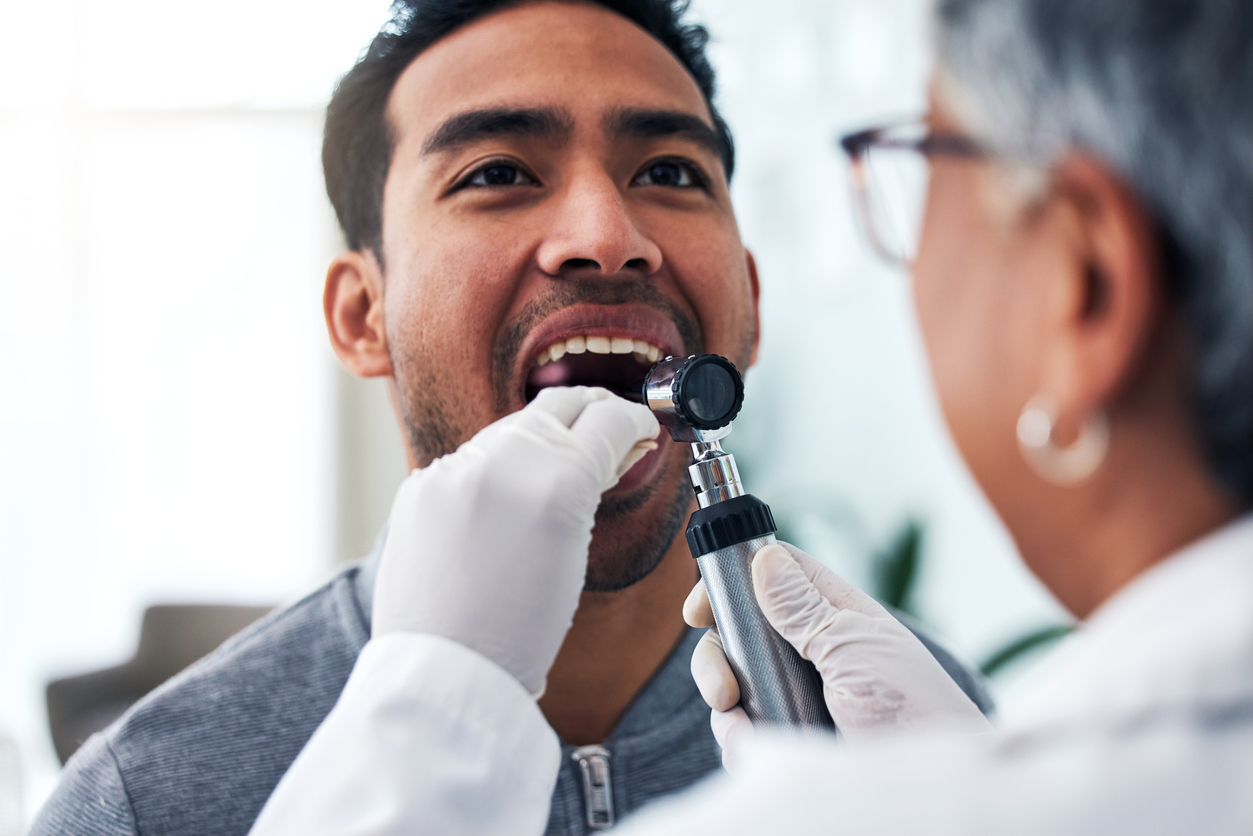 A dental professional examines a man's mouth.